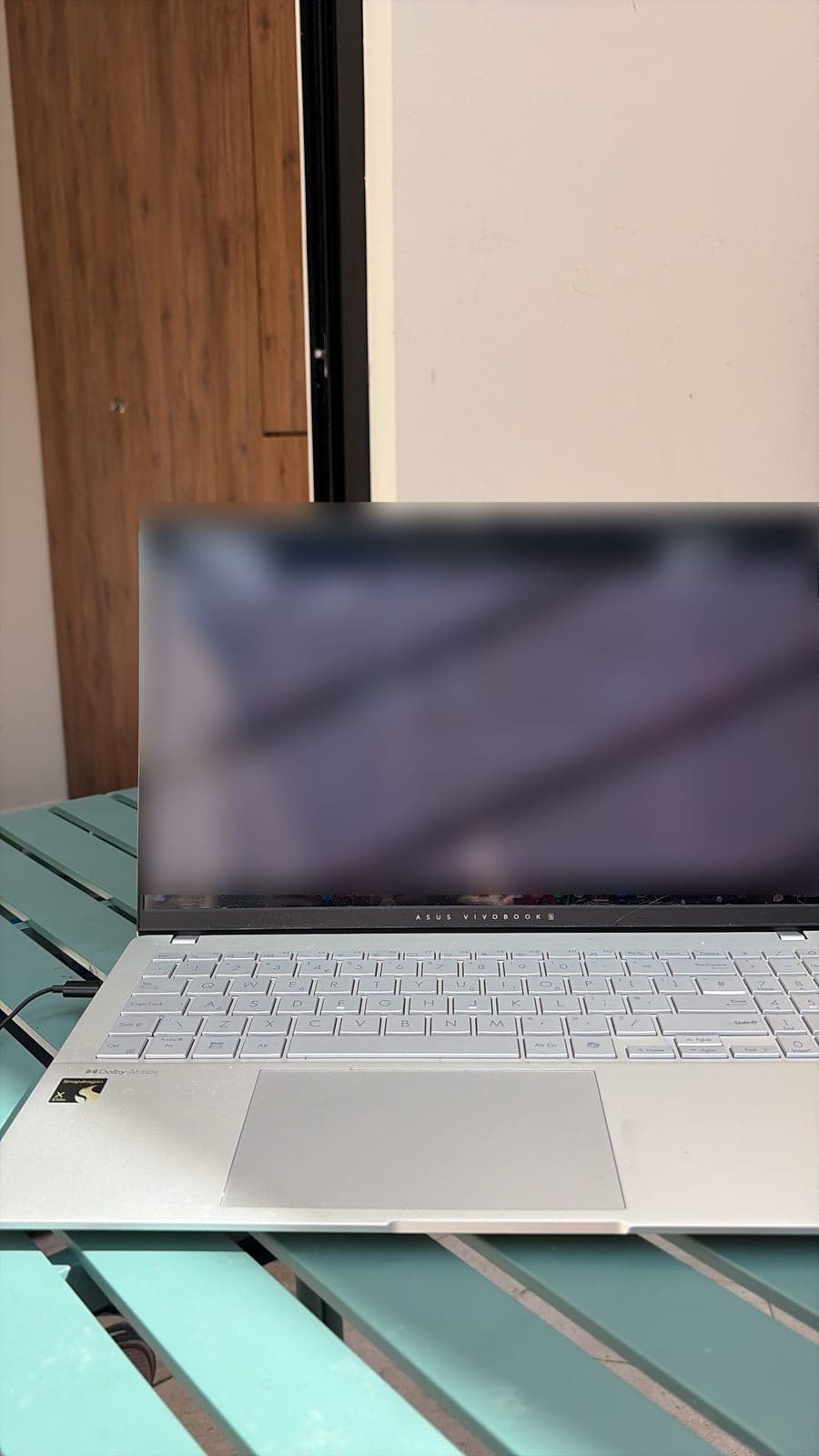 A laptop open on a green outdoor table in the sun